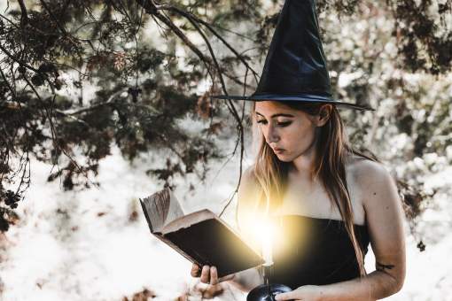jeune femme dans sorciere chapeau lecture livre dans foret