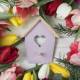 heart shape bird house surrounded with colorful tulips wooden desk